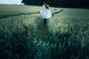 Woman in a white shirt walking through fields of crops on a farm
